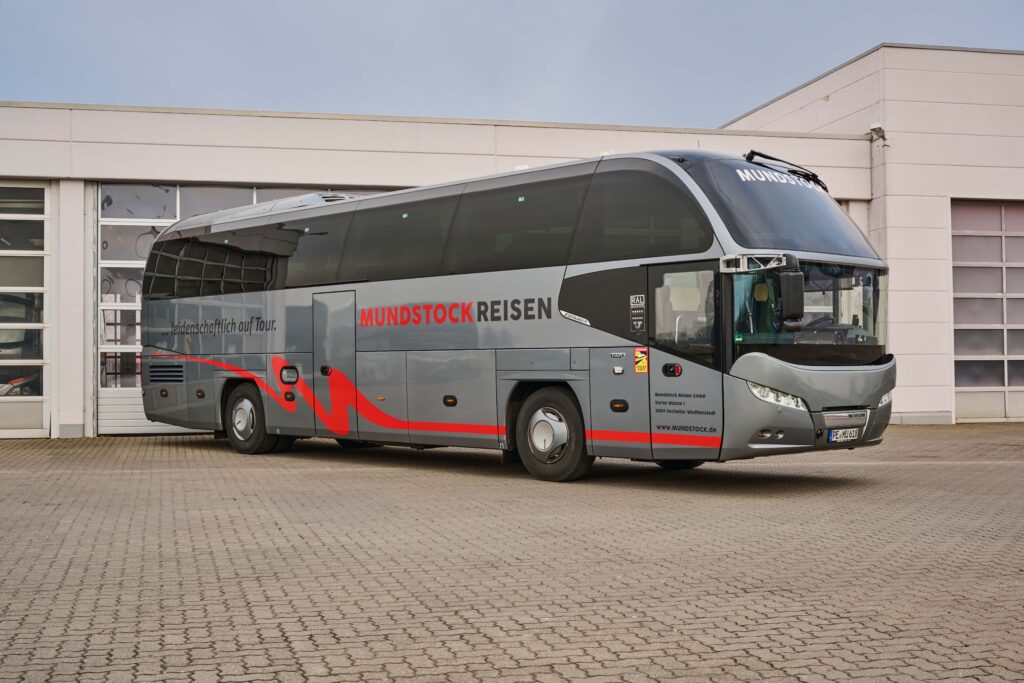 Ein VIP 5 Sterne Reisebus. Der komfortable Bus ist grau mit dem Mundstock Reisen Logo drauf.